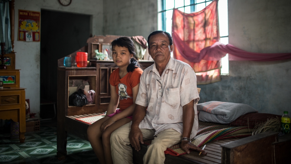 Sang and his 12-year-old daughter at home in Tay Ninh province, southwest Vietnam. 'I just want her to come back. We never expected it to be this hard - for her to leave the home, her children and relatives here,' he says [Yen Duong/Al Jazeera]
