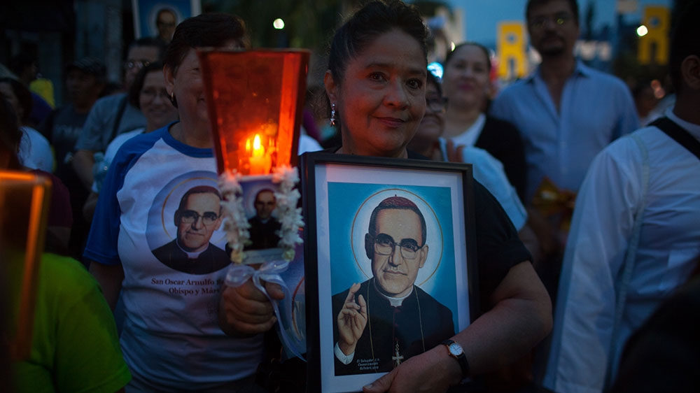 A woman carries an image of Saint Romero during the march on Saturday [Jeff Abbott/Al Jazeera]