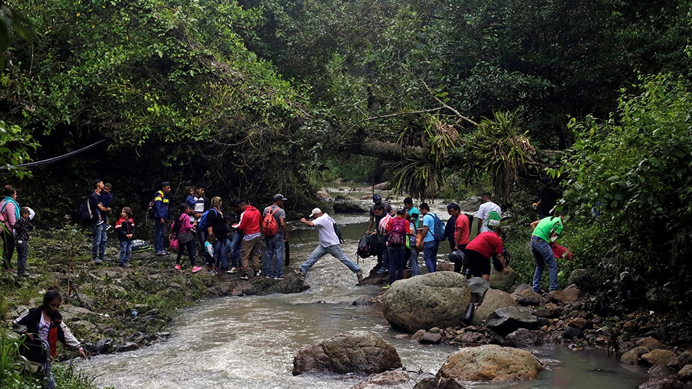 Honduran migrants cross the Lempa river, on the border between Honduras and Guatemala, to cross into Guatemala to join a caravan trying to reach the US [Jorge Cabrera/Reuters]