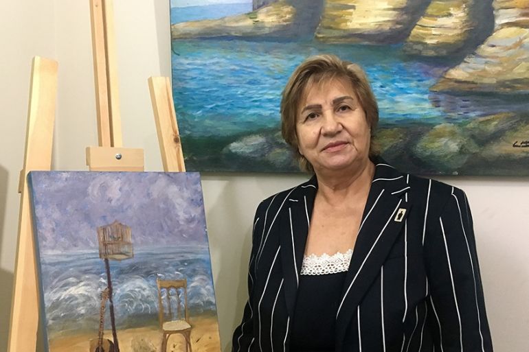 Mariam Saidi, whose son disappeared in 1982, stands in front of a painting she made to exemplify the absence of her child. On her jacket, a small brooch which represents the void let by the disappeare