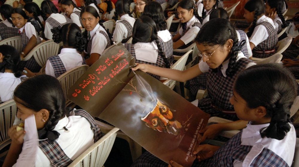 Students in Hyderabad look at a poster reading, 'Stop drug addiction before you are finished' [Krishnendu Halder/Reuters]