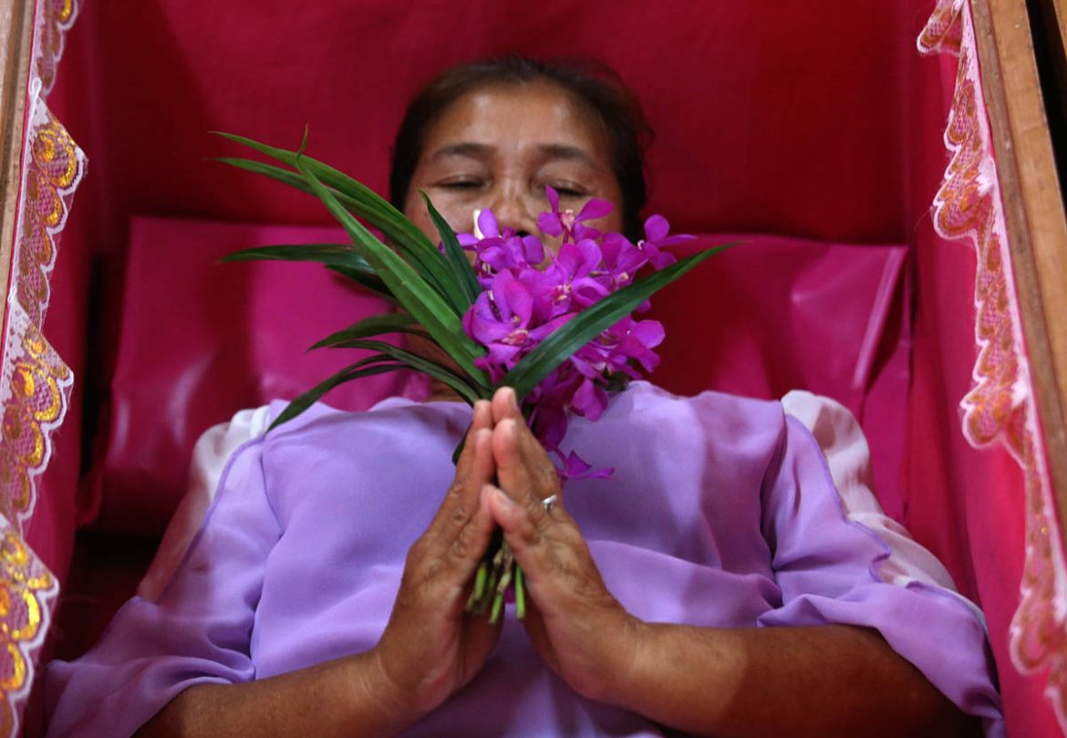 A worshipper prays as she takes her turn lying in a coffin at the Takien temple in suburban Bangkok, Thailand Monday, Dec. 31, 2018. Worshippers believe that the coffin ceremony – symbolizing death an