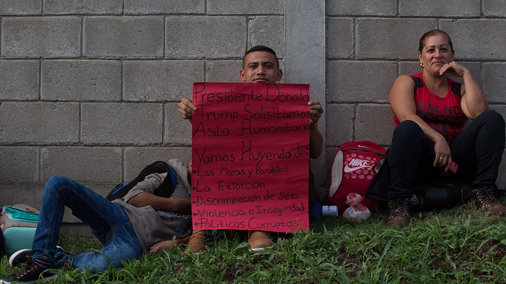 Carlos Maldonado holds a sign addressed to Trump outside the San Pedro Sula bus station [Jeff Abbott/Al Jazeera] 