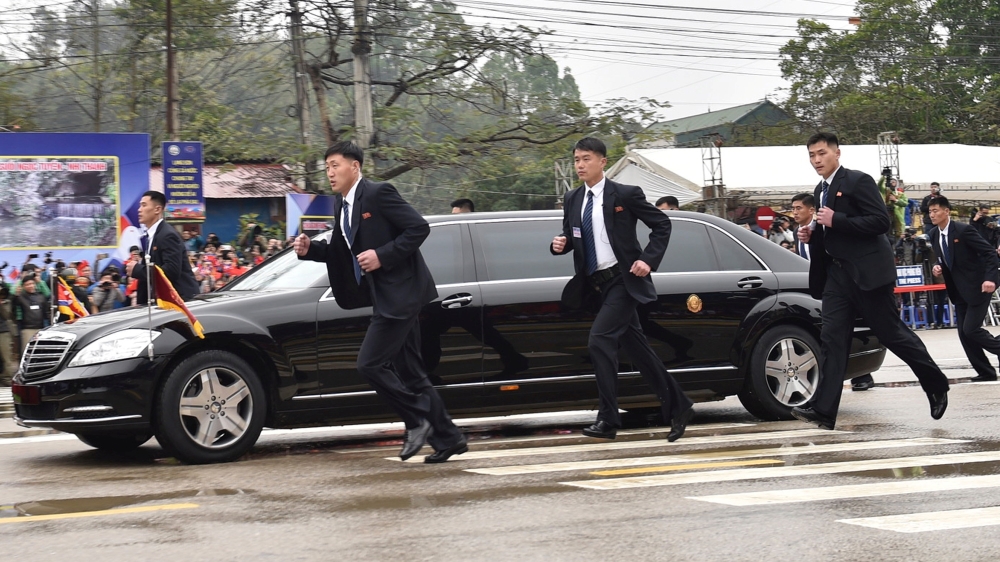 North Korean bodyguards run alongside a limousine transporting Kim [Reuters]