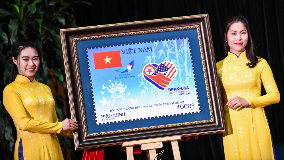 Two Vietnamese women display an enlarged frame of a stamp published to commemorate the second US-North Korea summit [Ye Aung Thu/AFP]