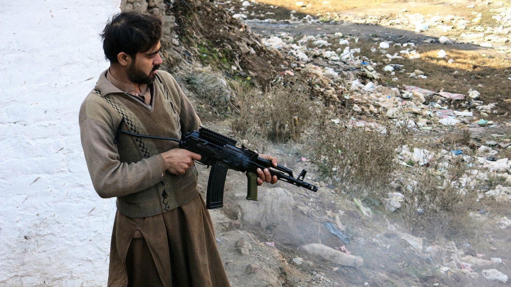 Customers test their newly purchased rifles by firing into a ditch behind the market [Asad Hashim/Al Jazeera]