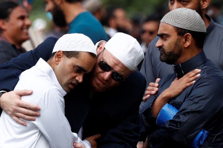 People comfort each other before the Friday prayers at Hagley Park outside Al-Noor mosque in Christchurch