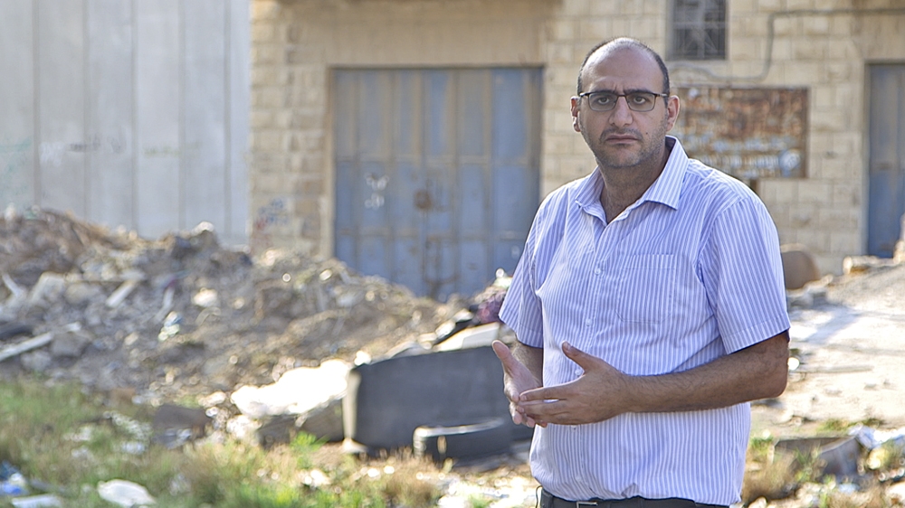 Omar Harami stands in a 'ghost town' in occupied East Jerusalem, where Israeli walls and borders have created empty neighbourhoods that once thrived [Al Jazeera]