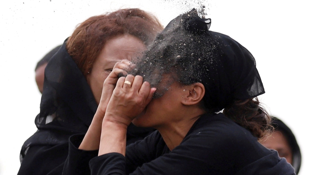 A relative puts soil on her face as she mourns at the scene of the crash [Tiksa Negeri/Reuters]