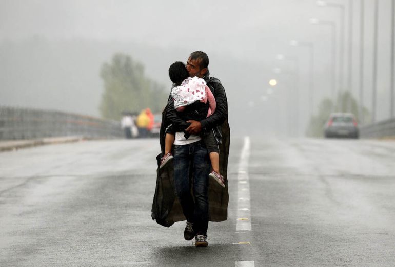 FILE PHOTO: A Syrian refugee kisses his daughter as he walks through a rainstorm towards Greece''s border with Macedonia, near the Greek village of Idomeni, September 10, 2015. REUTERS/Yannis Behrakis/