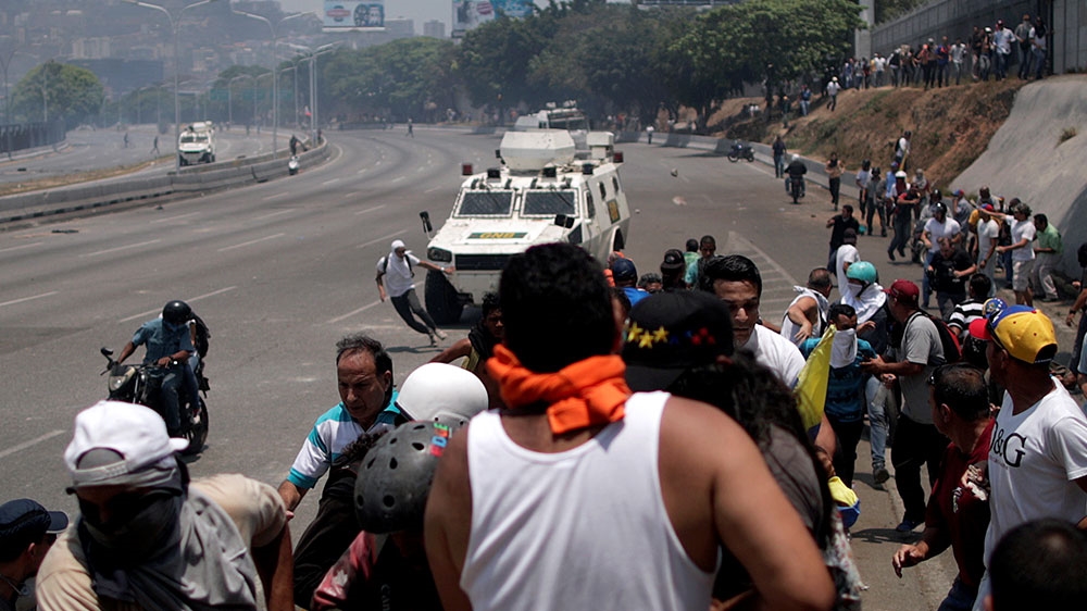 An opposition demonstrator runs before being struck by a Venezuelan National Guard vehicle as others watch from the side of the road, near the Generalisimo Francisco de Miranda Airbase in Caracas [Ueslei Marcelino/Venezuela] 