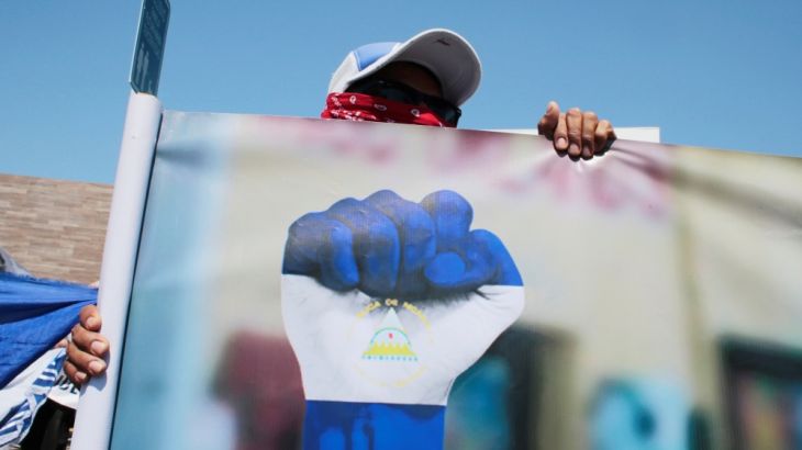An anti-government protester holds a banner and shouts slogans to riot police during a protest against Nicaraguan President Daniel Ortega''s government in Managua