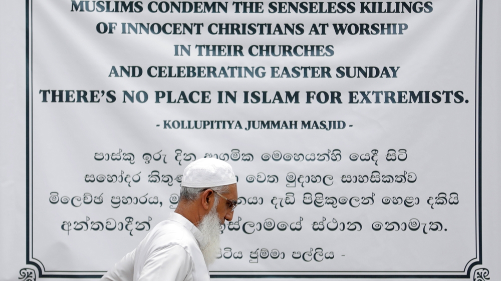 A Muslim walks past a banner on a mosque wall during the Friday prayers in Colombo [Dinuka Liyanawatte/Reuters]