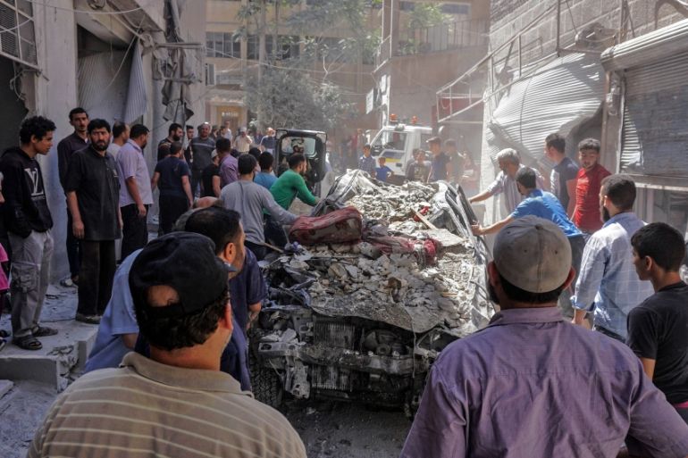 People push a car damaged by the debris of a building destoyed during an air strike by Syrian regime forces and their allies on the town of Ariha, in the southern outskirts of Syria''s Idlib province o