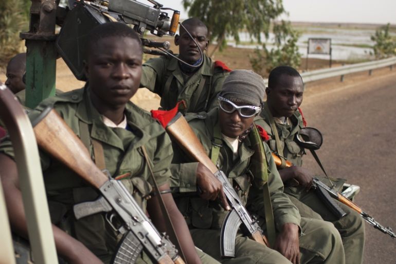 Malian soldiers ride in the back of a military pickup truck in Gao