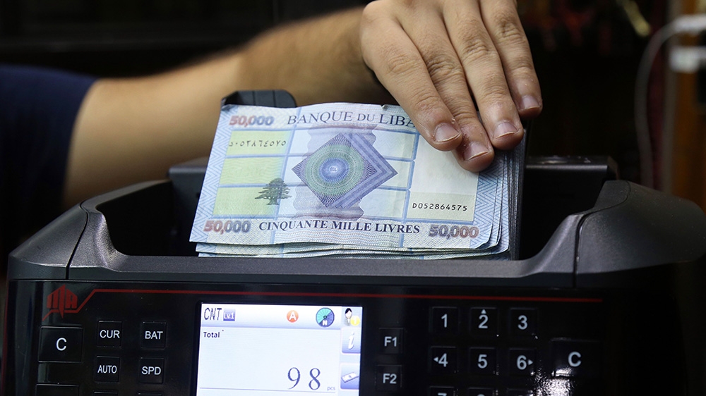 An employee places 50,000 denomination Lebanese pound banknotes in a money counting machine at a currency exchange store in Beirut, Lebanon, on Wednesday, Oct. 30, 2019