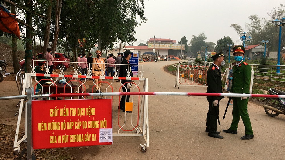 Police wearing masks guard a road checkpoint before entering the Son Loi commune in Vinh Phuc province, Vietnam, on Thursday, Feb. 13, 2020. 0fficial media reported that the Son Loi commune with 10,00
