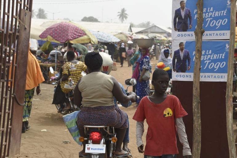 A motorbike taxi drive past campaign banners of Togolese President