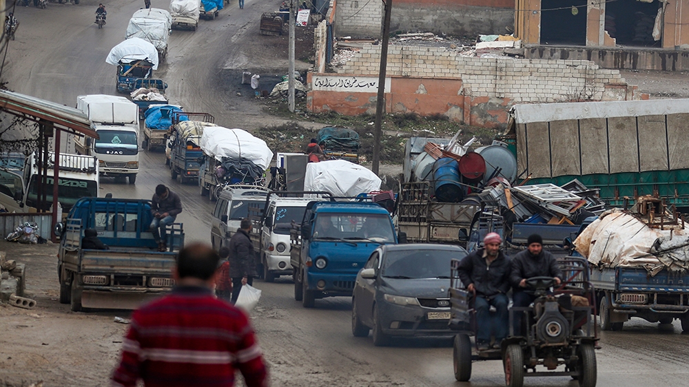 A convoy of trucks transporting Syrians and their belongings drives through the village of al-Mastuma, in the northern countryside of Syria's Idlib province on January 30, 2020, as thousands of people