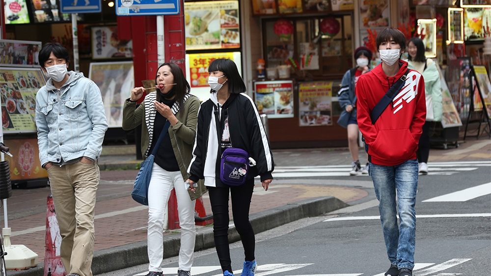 People wearing face masks to protect against the spread of the new coronavirus walk on a Yokohama China Town near Tokyo, Tuesday, March 31, 2020. (AP Photo/Koji Sasahara)