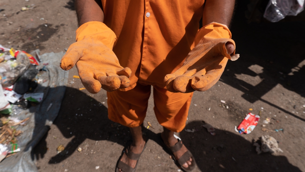 A contract worker shows the pair of gloves he received from the government, that became torn in a day [Shone Satheesh Babu/Al Jazeera]