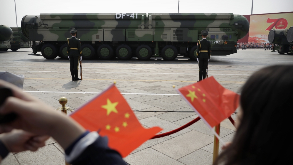 Spectators wave Chinese flags as military vehicles carrying DF-41 ballistic missiles roll during a parade to commemorate the 70th anniversary of the founding of Communist China in Beijing, Tuesday, Oc