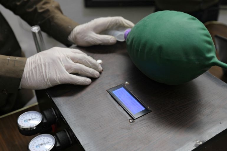 A volunteer wearing gloves builds a prototype ventilator