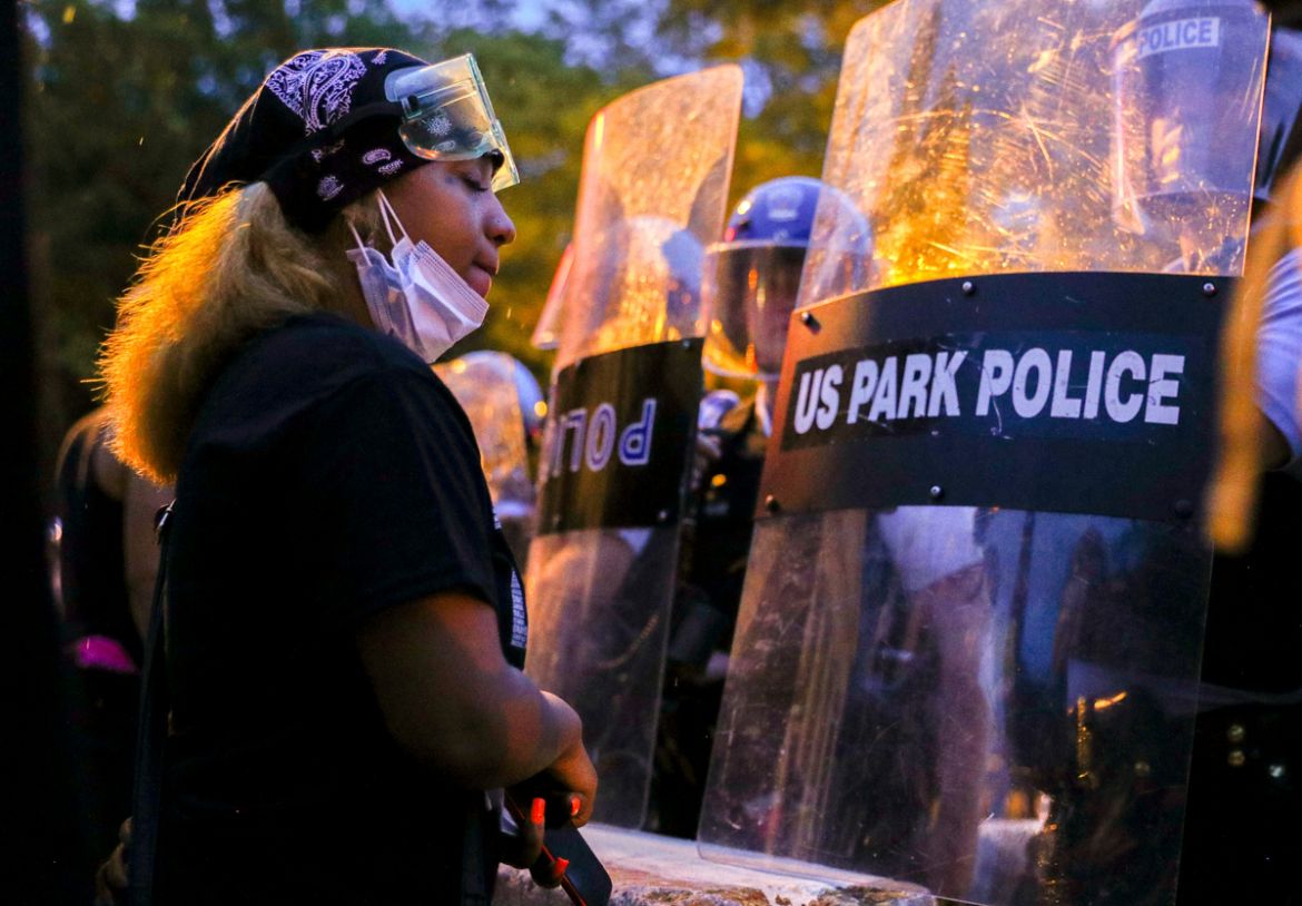 A protestor stands in front of a line of U.S. Park Police riot police as the two sides face off at Lafayette Park in front of the White House after police clashed with demonstrators trying to pull dow