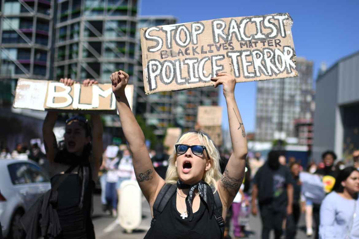 Demonstrators carry placards with slogans as they march in the road outside the US Embassy in London on May 31, 2020 to protest the death of George Floyd, an unarmed black man who died after a police