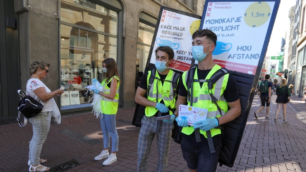 People wearing yellow vests hand out masks and information brochures where to wear the mandatory masks in the busiest streets of the city, during the coronavirus disease (COVID-19) outbreak,