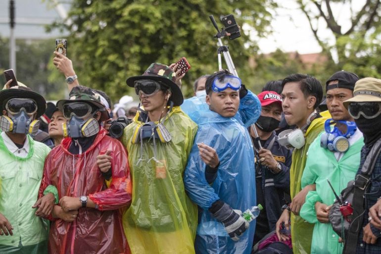 Pro-democracy protesters wearing masks sometimes used to avoid tear gas create a human chain during a march near Sanam Luang in Bangkok, Thailand, Sunday, Sept. 20, 2020. The mass student-led rally th