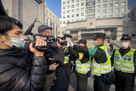 Police attempt to stop journalists from recording footage outside a court in Shanghai during the trial of Chinese citizen journalist Zhang Zhan [File: Leo Ramirez/AFP]