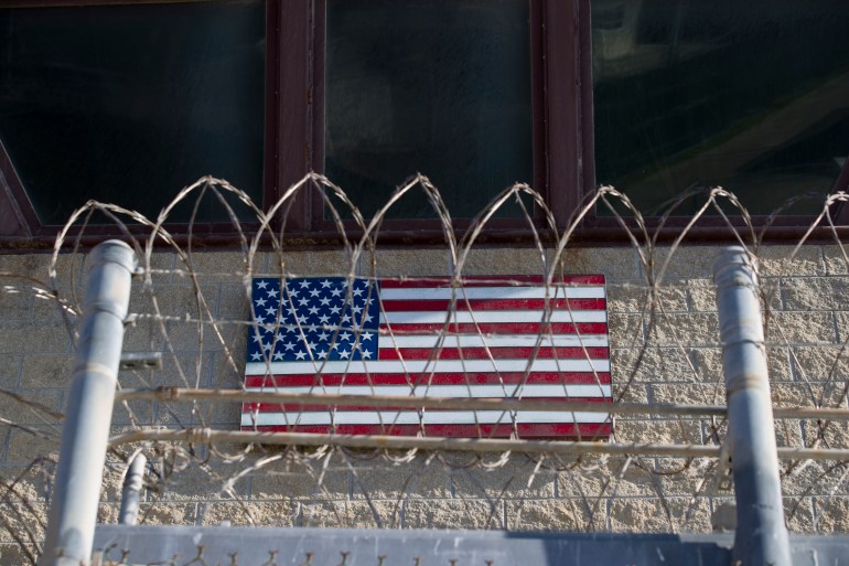 an American flag is seen through the razor wire on the control tower in Guantanamo Bay