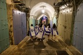 Israeli women cover themselves with Israeli national flags as they walk inside Jerusalem's Old City June 15, 2021. [Ronen Zvulun/Reuters]