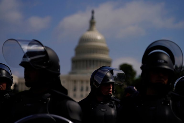 Police in riot gear with the US Capitol in the background.