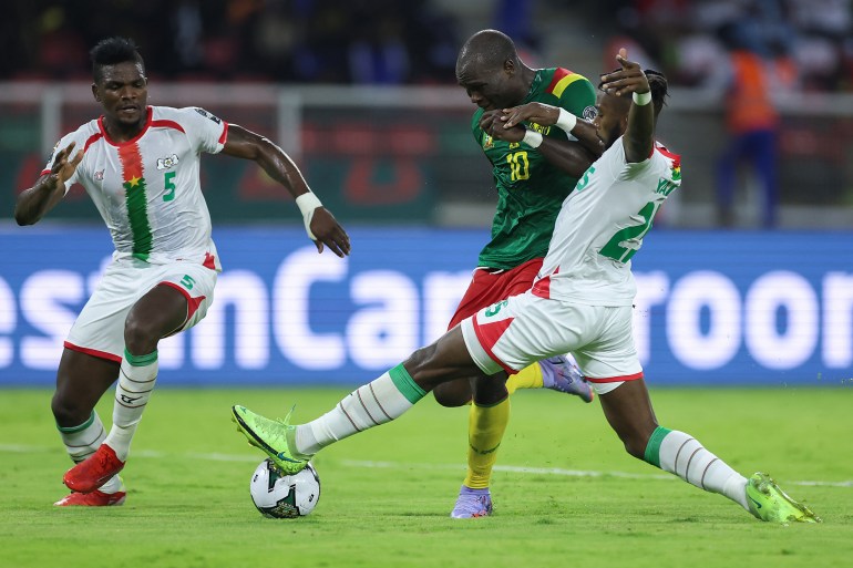 Cameroon's forward Vincent Aboubakar (C) is tackled by Burkina Faso's defender Steeve Yago