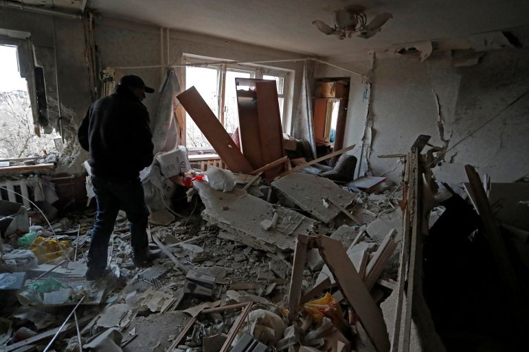 A resident walks inside a damaged apartment