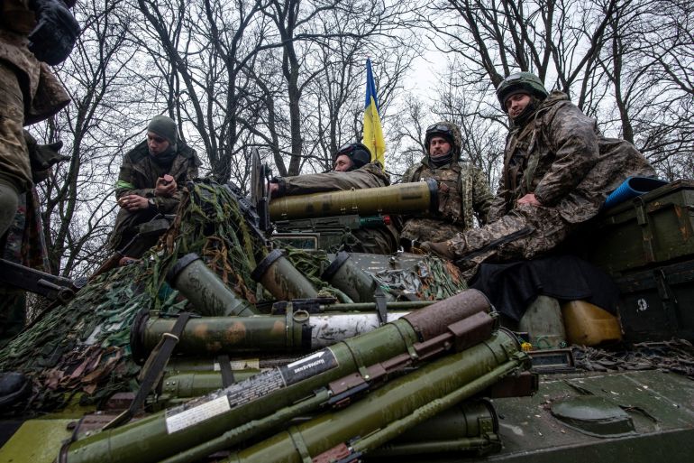 Ukrainian forces sit atop an armoured vehicle