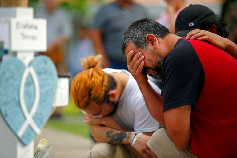 Vincent Salazar, right, father of Layla Salazar, weeps while kneeling in front of a cross with his daughter's name at a memorial site for the victims killed in this week's elementary school shooting in Uvalde, Texas.