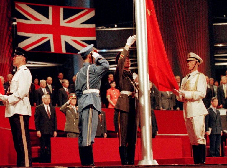 Soldiers stand in salute with the Chinese and British flags