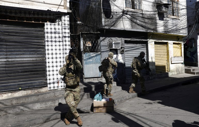 Police walking through a street with weapons drawn during the Rio favelas raid.