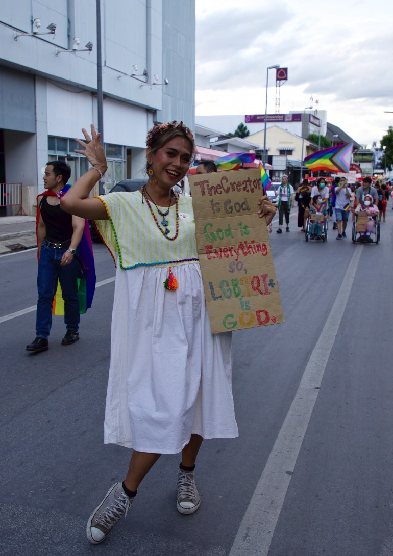 A Pride participant holds a handwritten placard saying: 'The creator is God. God is everything so LGBTQI+ is GOD' 