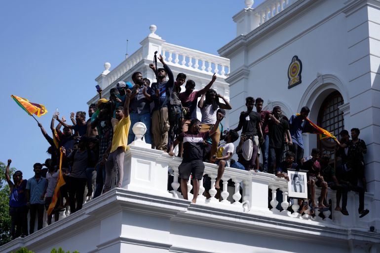 Sri Lankan protesters, some holding national flags, on a balcony after storming Prime Minister Ranil Wickremesinghe's office.