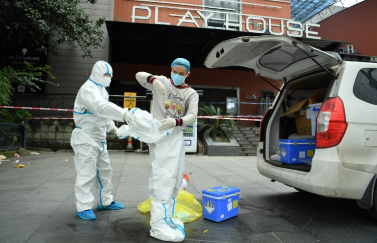 Workers in protective suits are seen outside a nightclub, which has been closed after new cases of the coronavirus disease