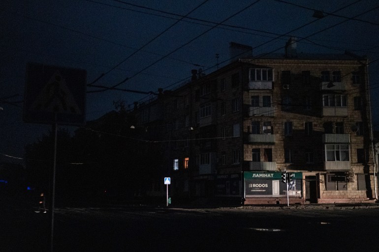 A man crosses a pitch-black street in Kharkiv.