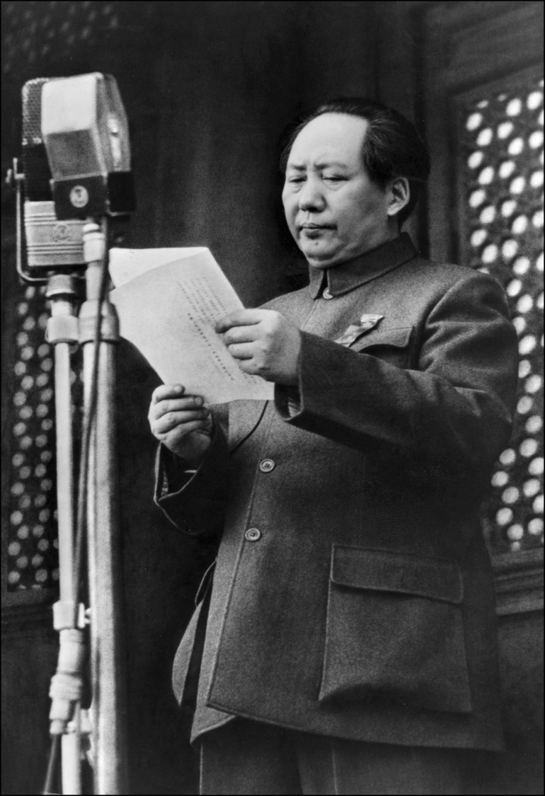 Black and white photo showing Mao Zedong standing at a microphone to declare the People's Republic of China at the ed of the civil war