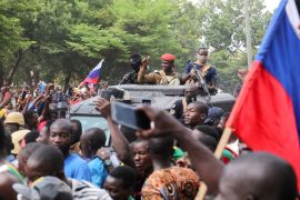 Burkina Faso&#039;s leader Ibrahim Traore is welcomed by supporters holding Russian flags in an armoured vehicle in Ouagadougou, Burkina Faso [File: Vincent Bado/Reuters]