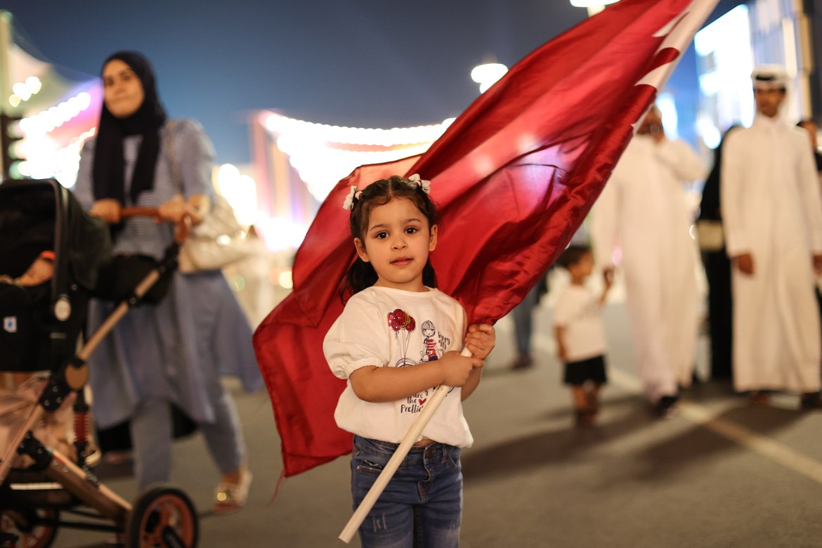 A child holds a Qatari flag.