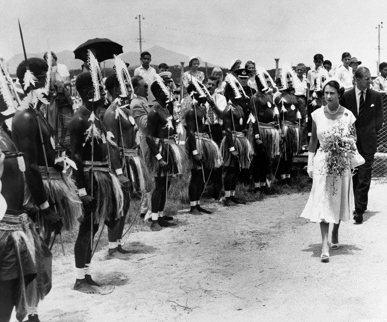 A black and white photo showing Torres Strait Islanders standing in a line as Queen Elizabeth walks past during a 1954 visit to Australia