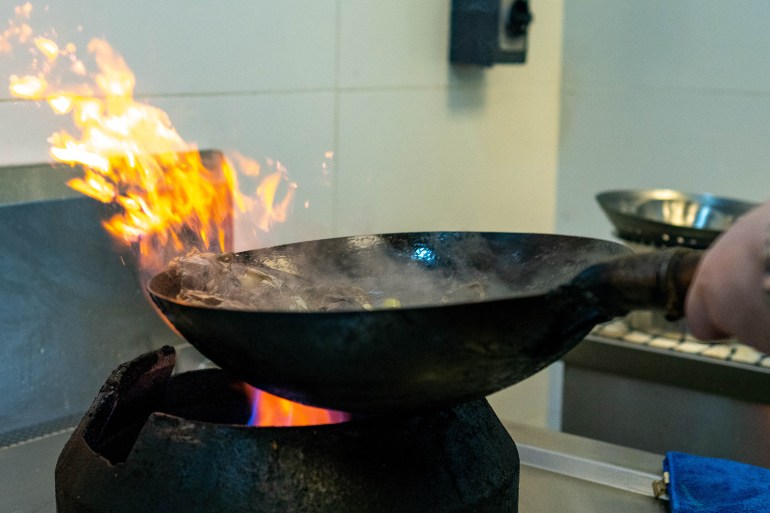 a wok caught mid-toss over an open flame